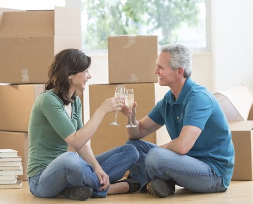 A couple who just moved into their home are surrounded by boxes.