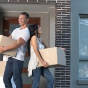 A couple holding boxes and moving out of their apartment.