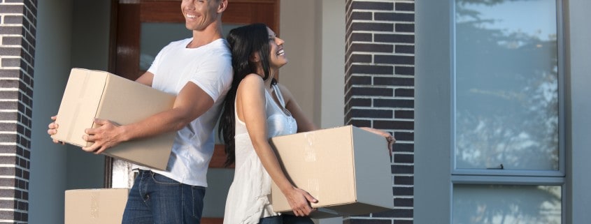 A couple holding boxes and moving out of their apartment.