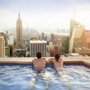 Couple in a pool overlooking the city and large buildings. Living the condo life.
