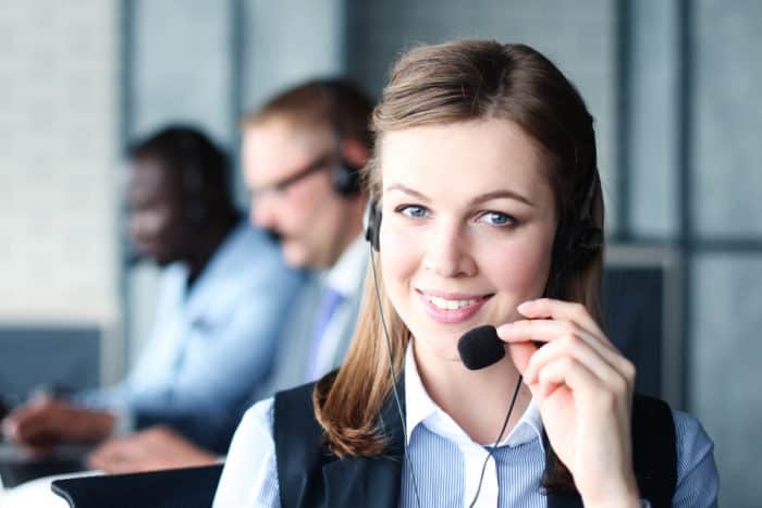 Image of a customer support person talking through a headset and smiling.