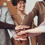 A group of people joining hands, and exemplifying teamwork. Blog article - learn about the top goals that HOA management companies should focus on in 2023.