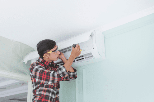 Maintenance person fixing an AC unit. Learn how to reduce workload for your staff.